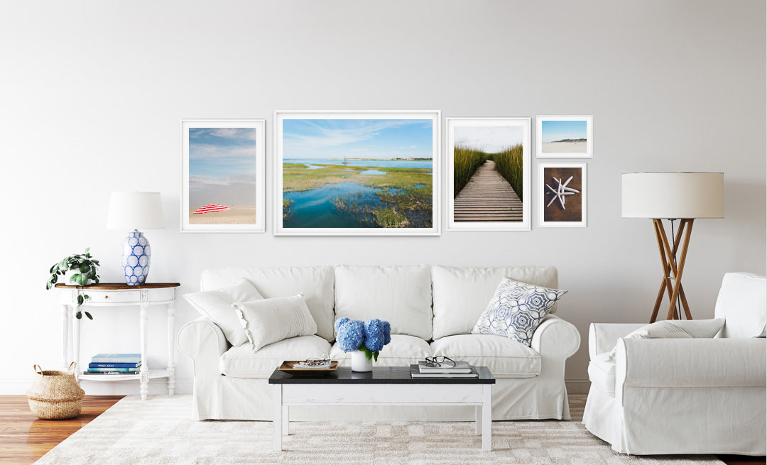 Beach Photographs of Cape Cod in a beach inspired home, a photograph of a red and white beach umbrella, a photograph of a boat in an open waters and marshland, photograph of the Wellfleet boardwalk, Mayflower beach photograph, two white starfish