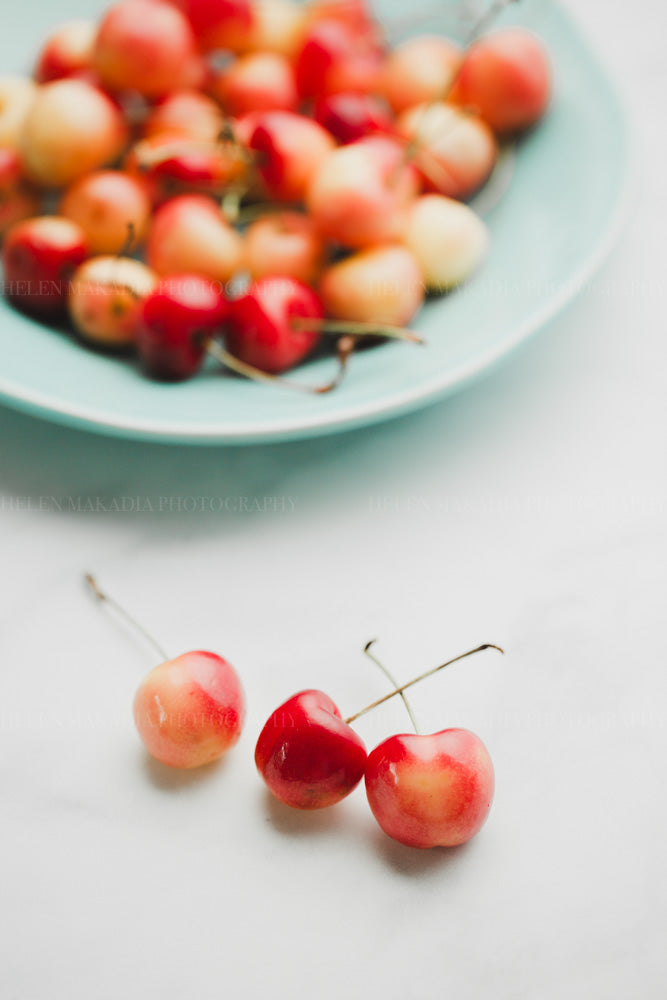 photograph of colorful rainier cherries on a blue platter