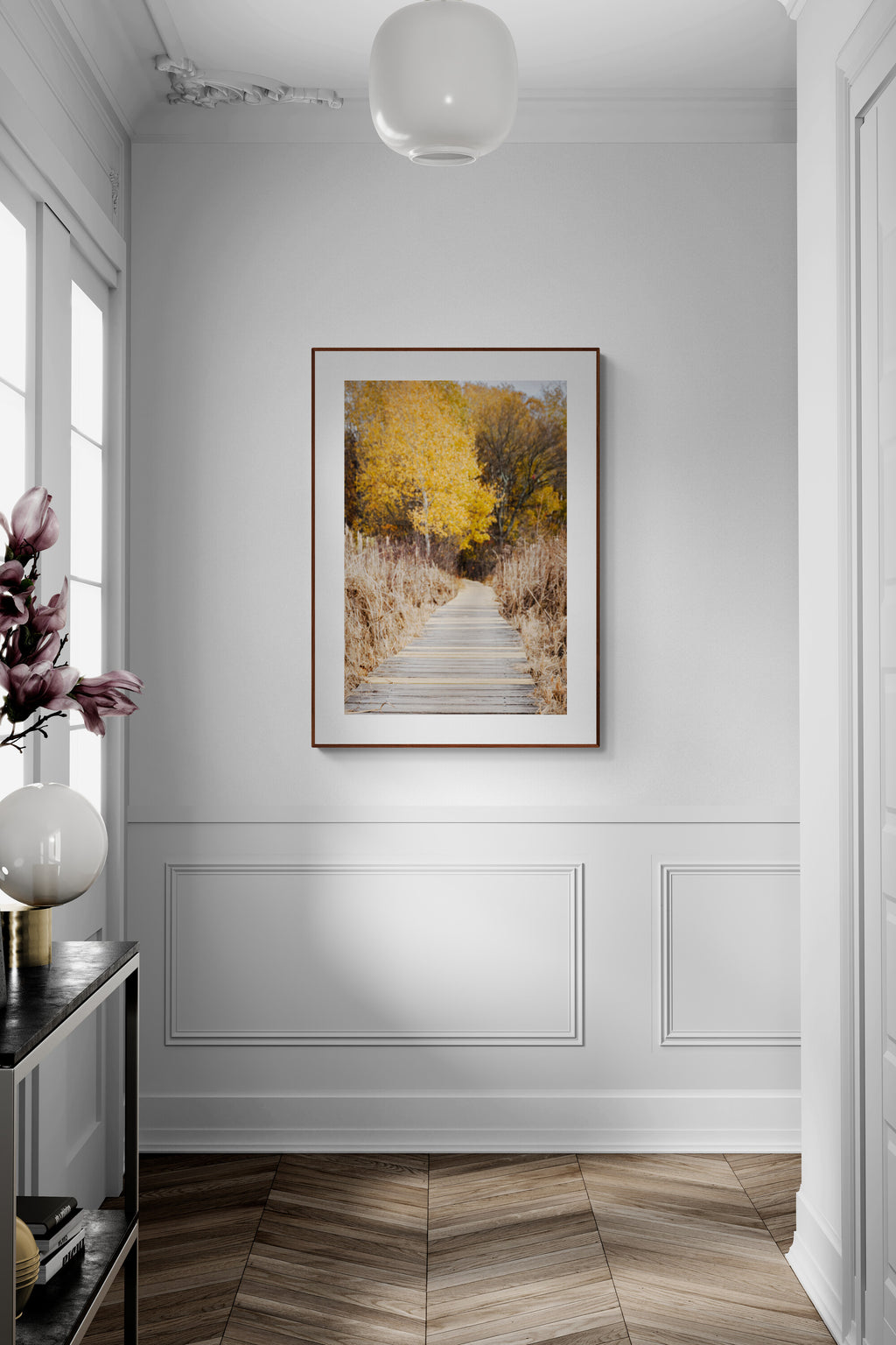Framed photograph of a boardwalk and nature path as wall art in an entryway.