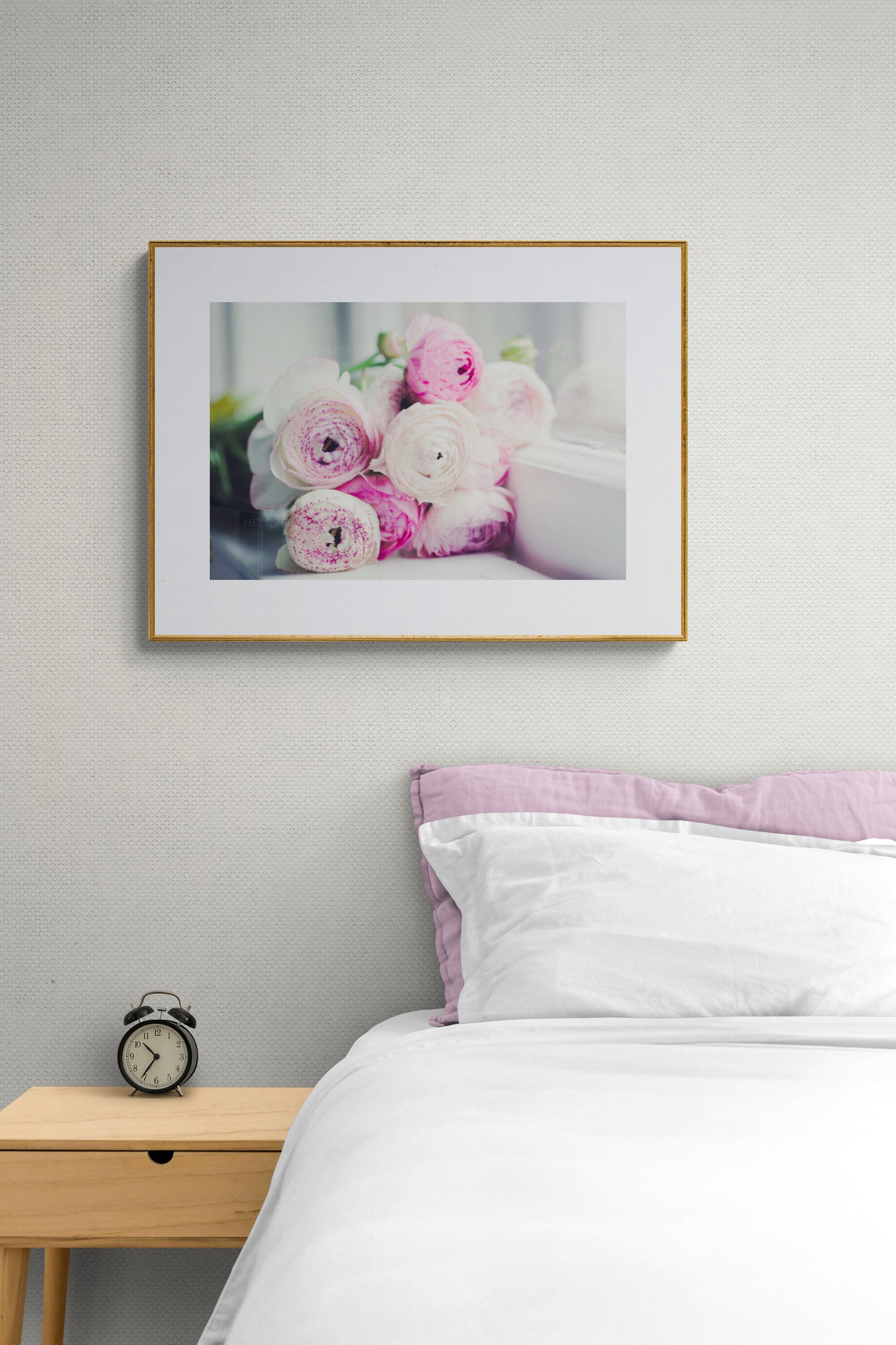 A photograph of lavender pink ranunculus flowers in a guest room as wall art decor.