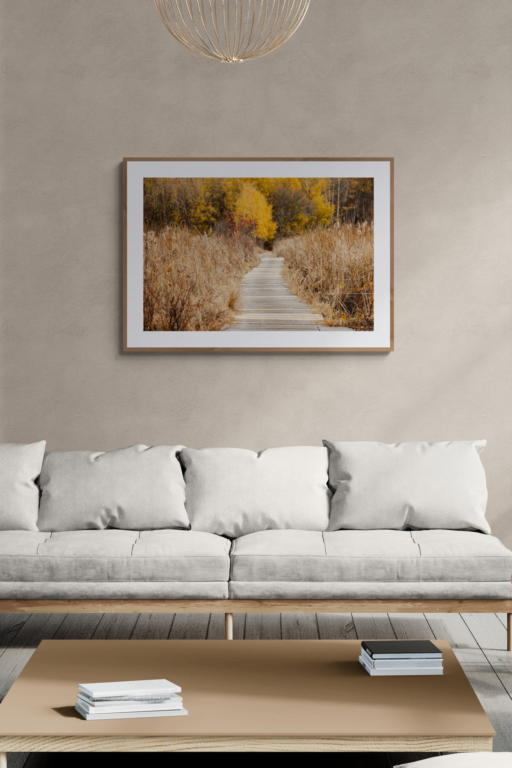 A framed nature photograph of a boardwalk and fall foliage in a living room