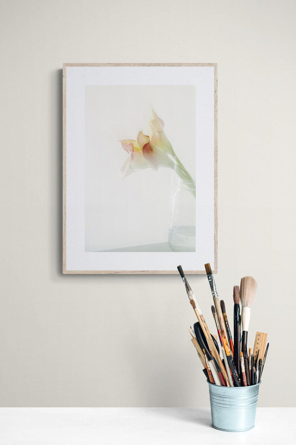 a photograph of pink calla lilies in a jar as wall art print in a personal art studio.