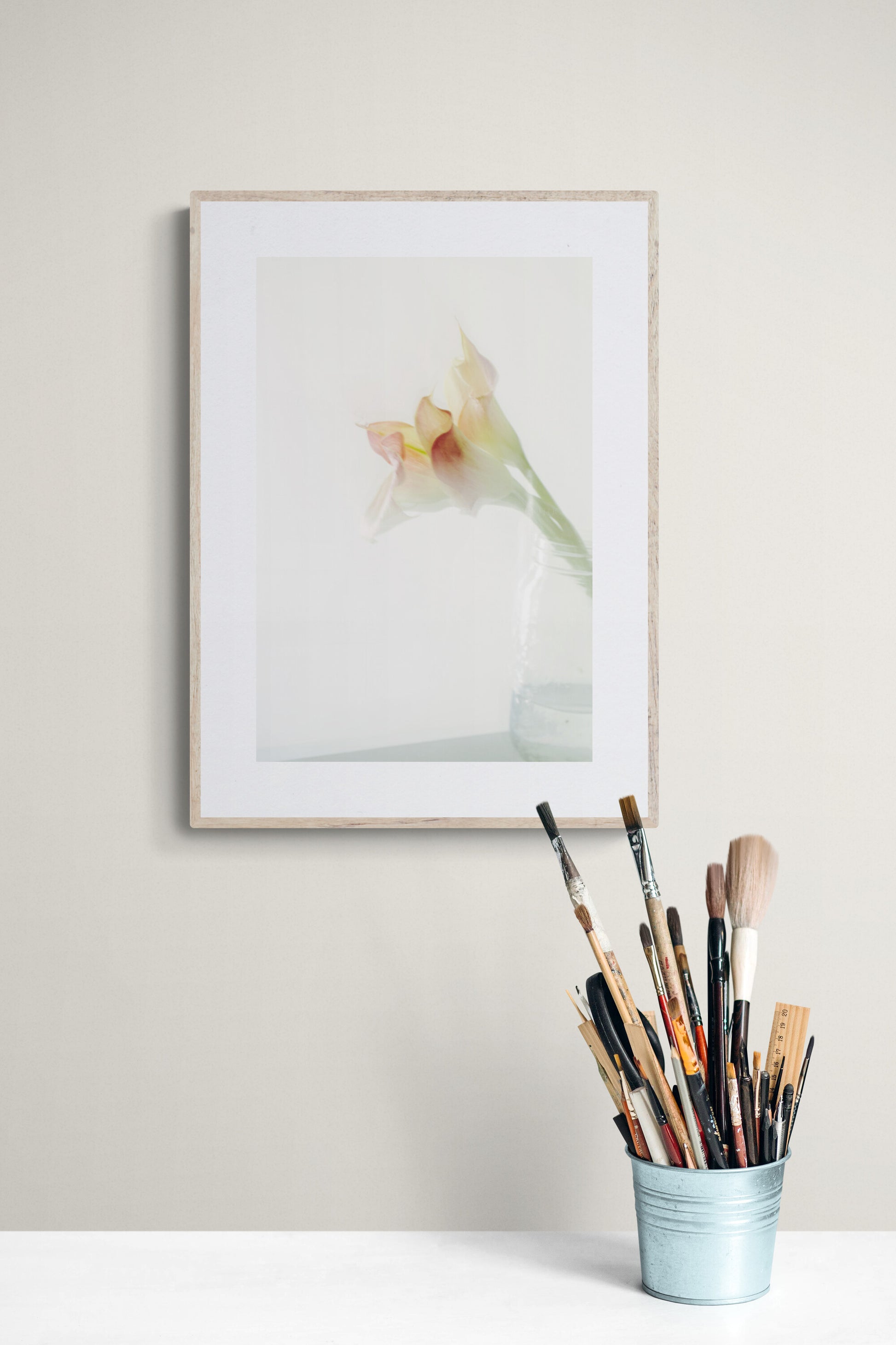 a photograph of pink calla lilies in a jar as wall art print in a personal art studio.