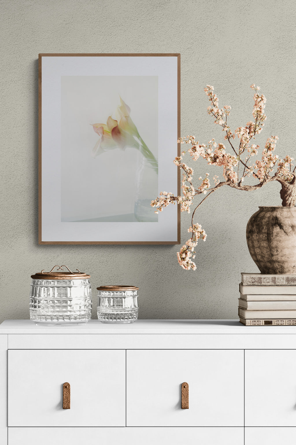 a photograph of pink calla lilies in a jar as wall art print in a bedroom.