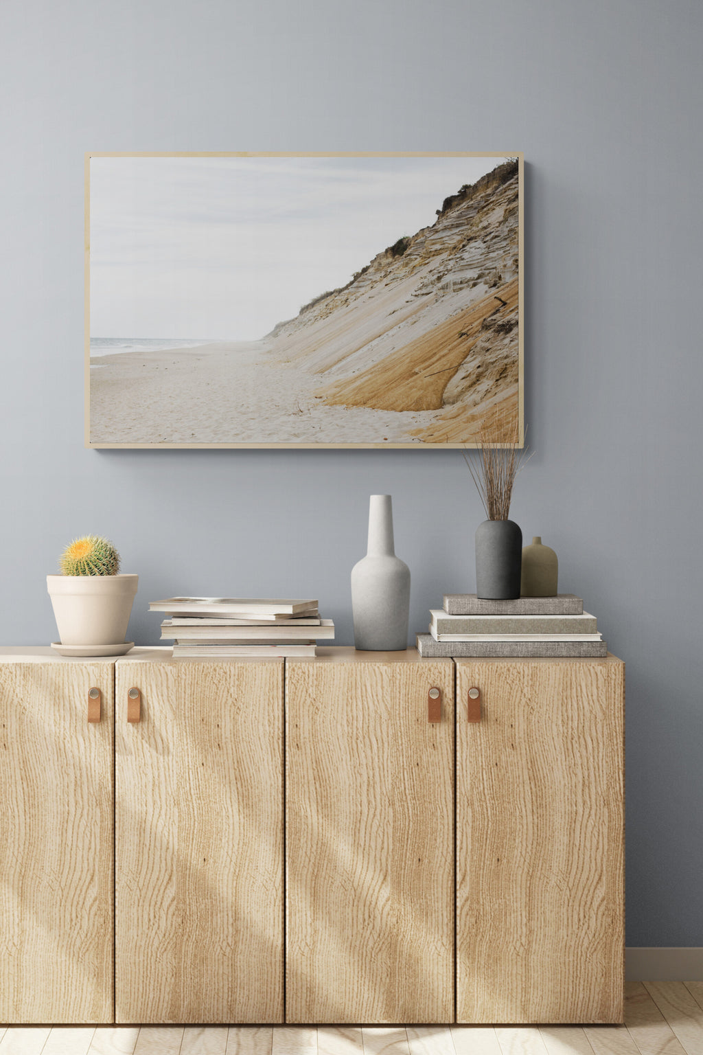 A landscape Cape Cod photograph of sand dunes and oceanas wall art in a living room sideboard.