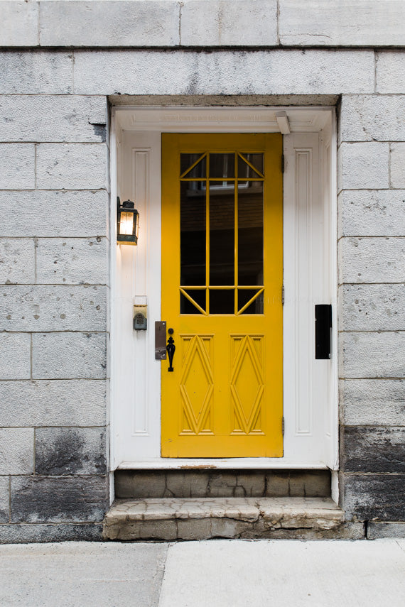 A yellow wooden ornate door in old quebec city, surrounded by stone