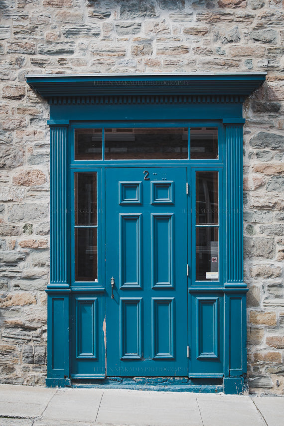 Photograph of Intricate blue Door with wood trim surrounded by stone wall and floor in Quebec City Canada